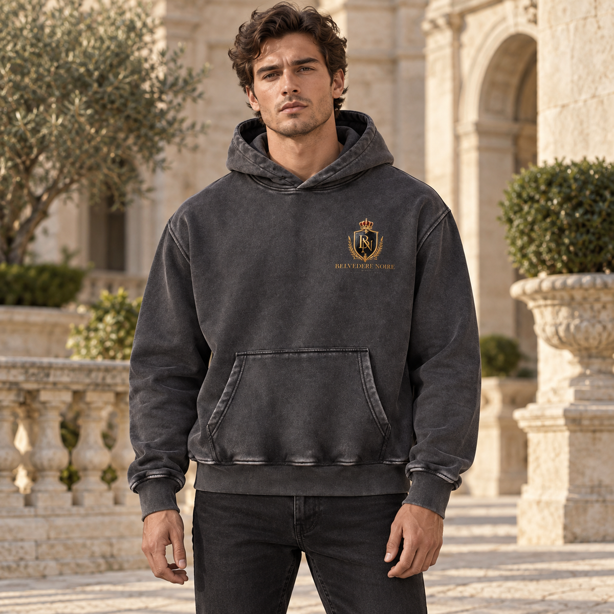 BELVEDERE NOIRE charcoal washed hoodie, male model in courtyard, AI styling mockup